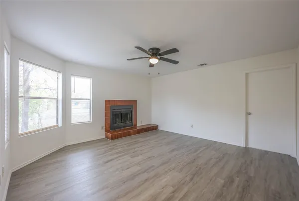 an empty room with windows and a ceiling fan
