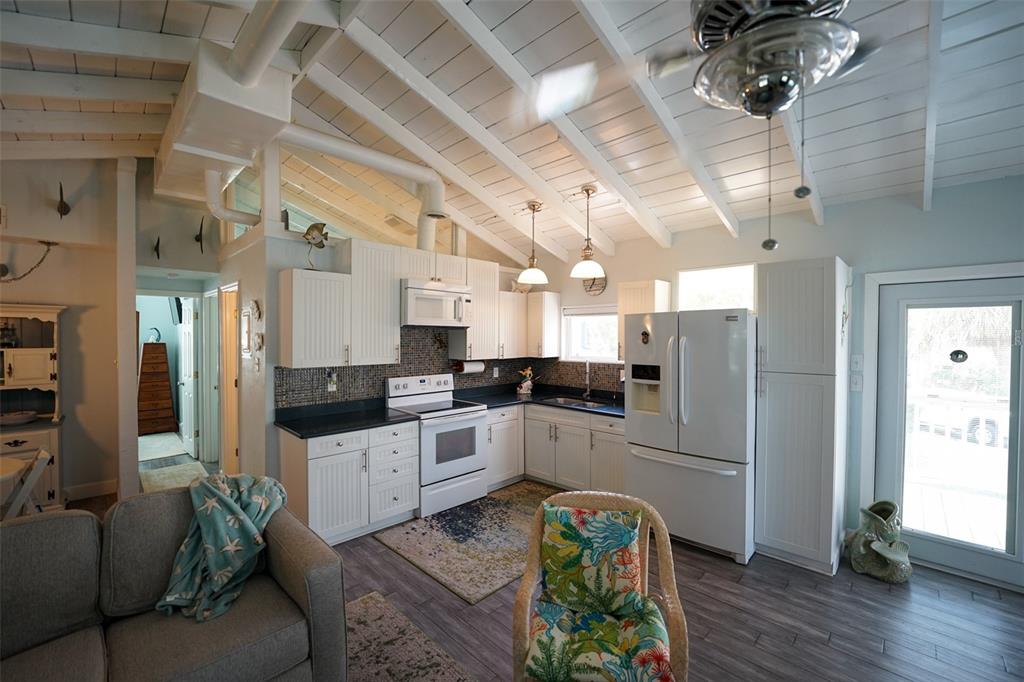 3480 Harbor Drive Weeki Wachee, FL 34607 - Photo 13 of 31 a kitchen with stainless steel appliances kitchen island granite countertop a refrigerator a stove a sink dishwasher and a dining table with wooden floor