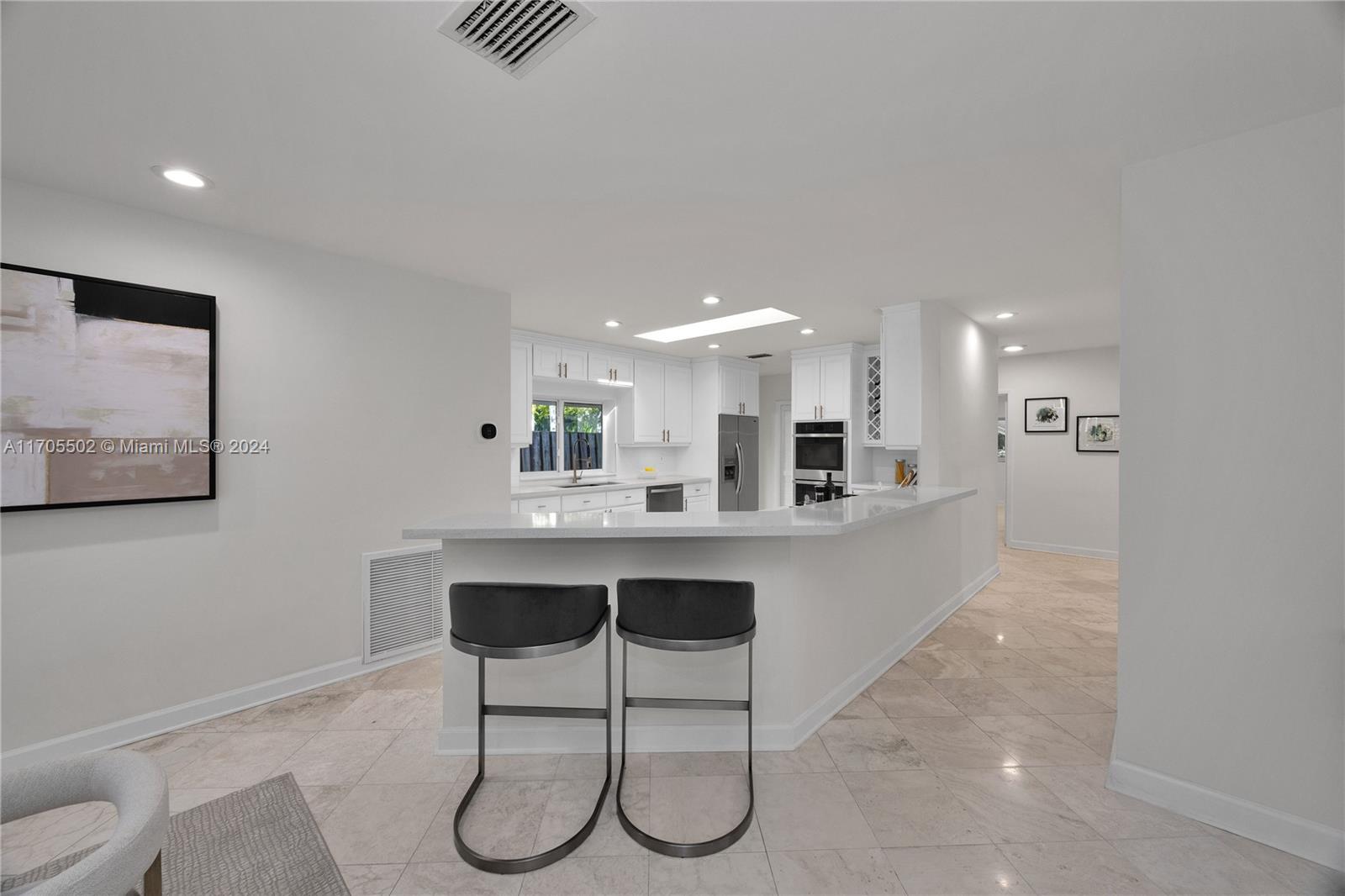 3566 Rockerman Road Miami, FL 33133 - Photo 14 of 43 a large white kitchen with a sink and chairs