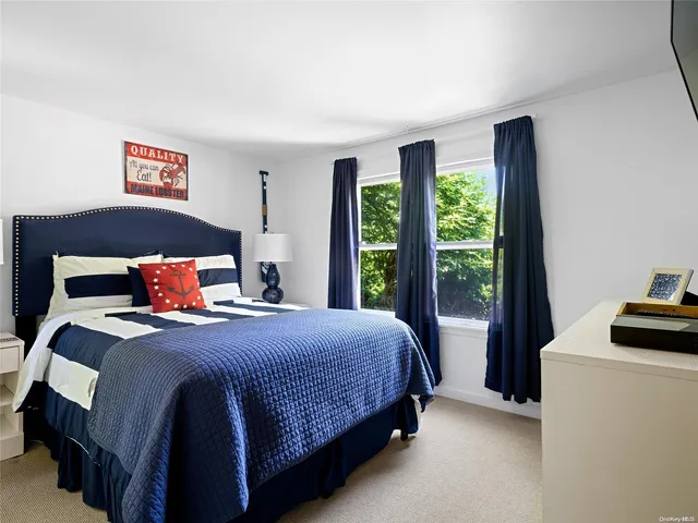 a bedroom with a bed and a dresser next to a window