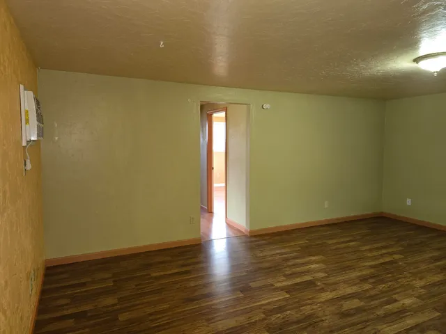 a view of an empty room with wooden floor and a window