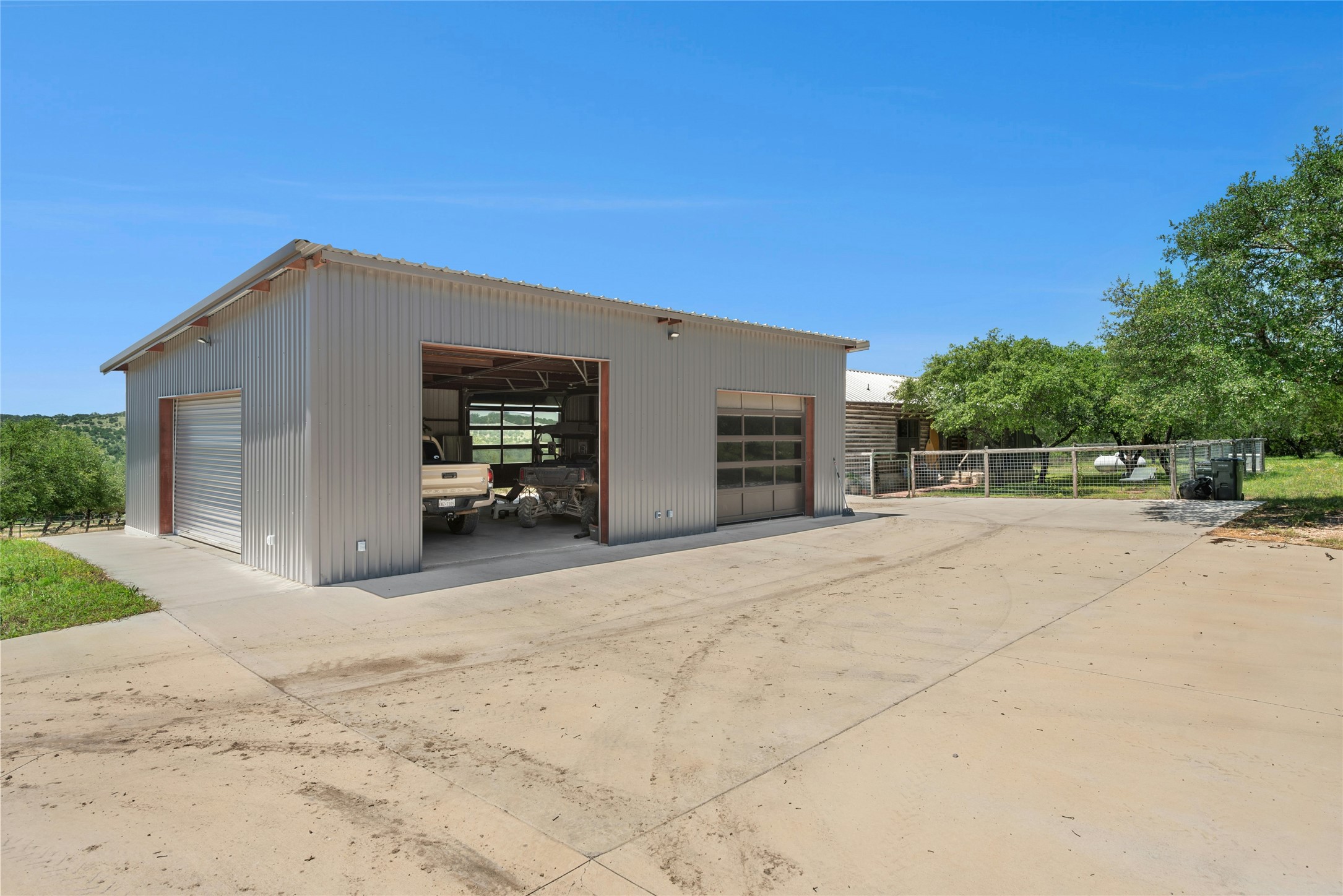 496 Middleton Road Spicewood, TX 78669 - Photo 36 of 40 Spacious metal structure featuring corrugated siding, a roll-up garage door, and an overhead glass-paneled door