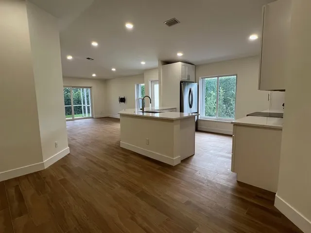 an open kitchen with kitchen island wooden floors and stainless steel appliances