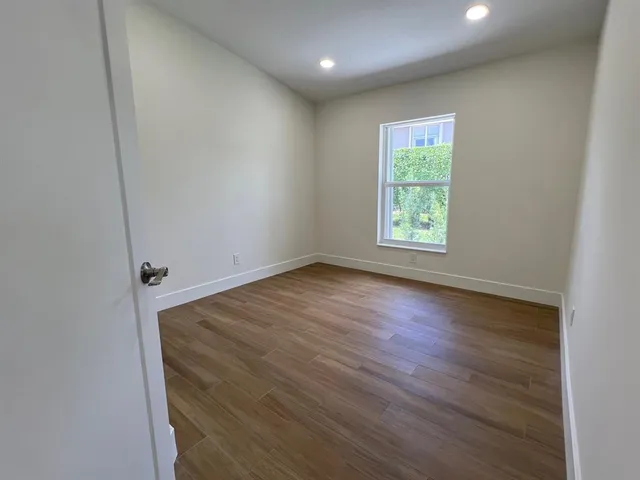 an empty room with wooden floor and windows