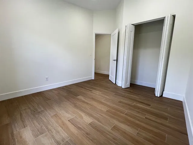 an empty room with wooden floor and closet