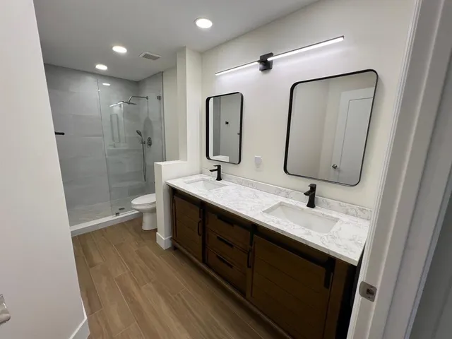 a bathroom with a double vanity sink mirror and shower
