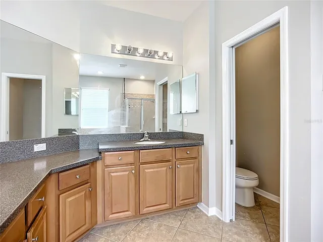 a bathroom with a granite countertop sink a toilet a mirror and bathtub
