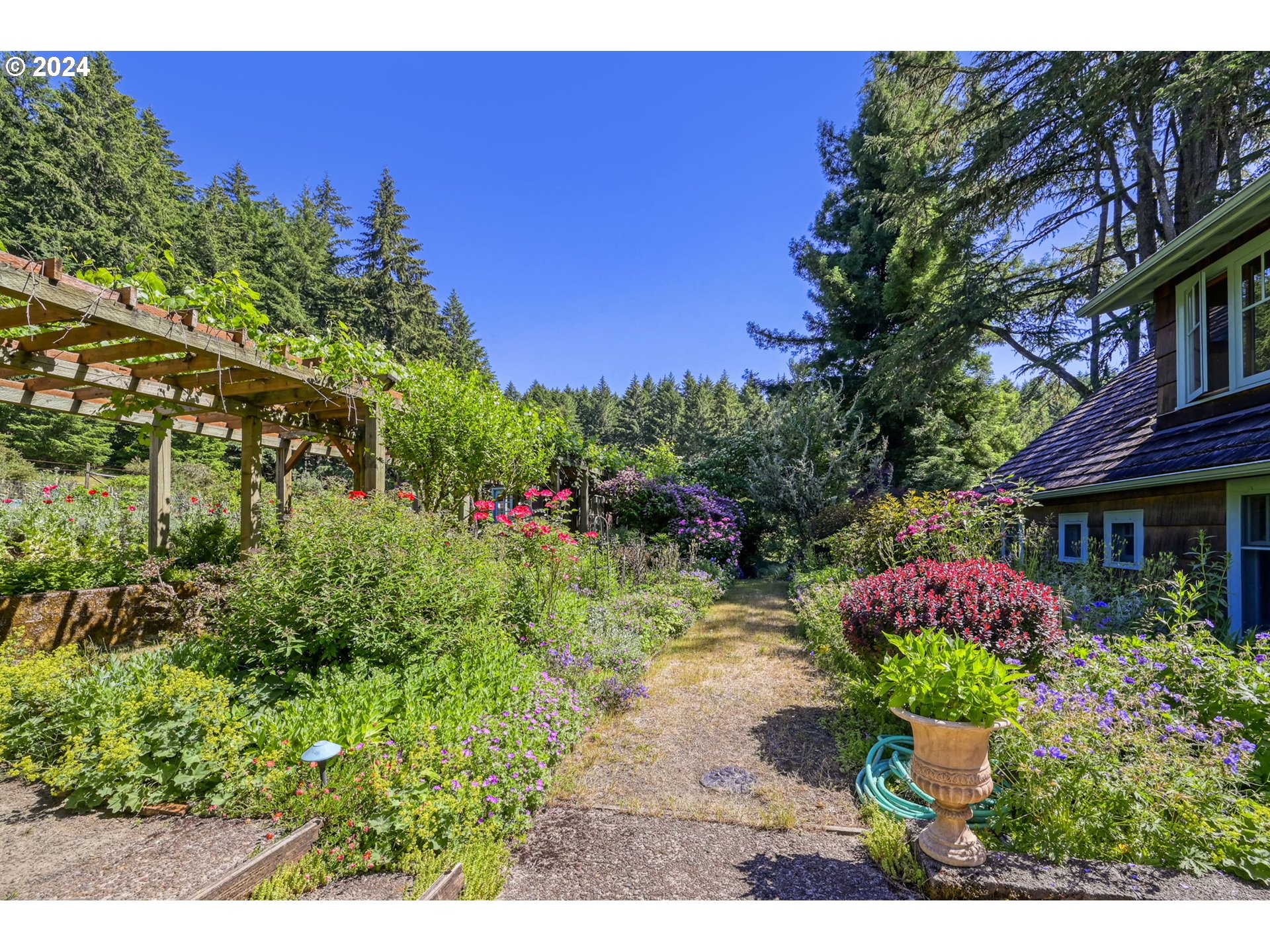 36245 Wagner Lane Cottage Grove, OR 97424 - Photo 26 of 45 a view of a garden with a lot of flower plants and wooden fence