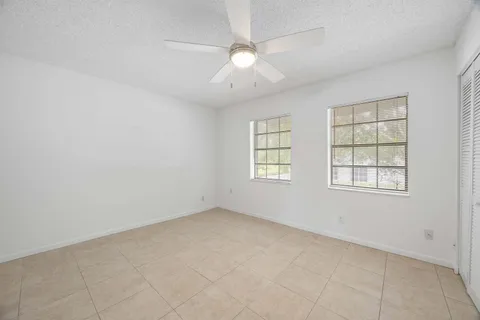 an empty room with windows and fan