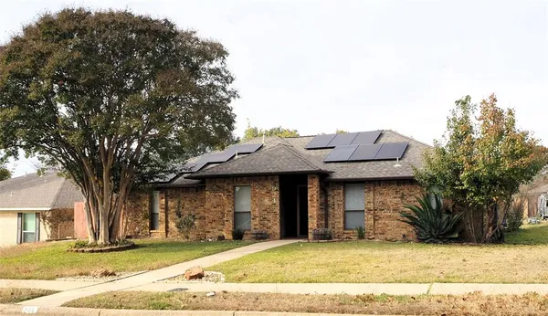 a front view of a house with a garden and tree