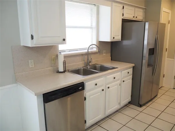 a kitchen with white cabinets and a refrigerator