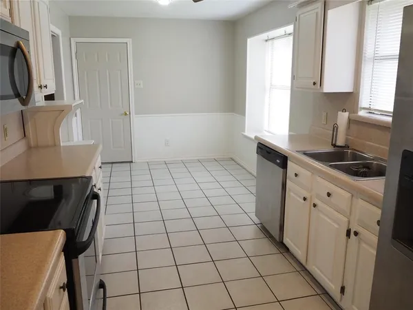 a kitchen with a sink a stove and white cabinets