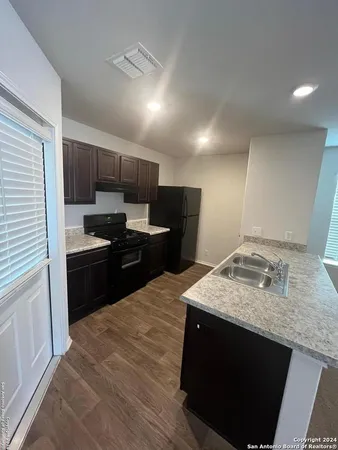 a kitchen with a sink and a stove top oven with wooden floor