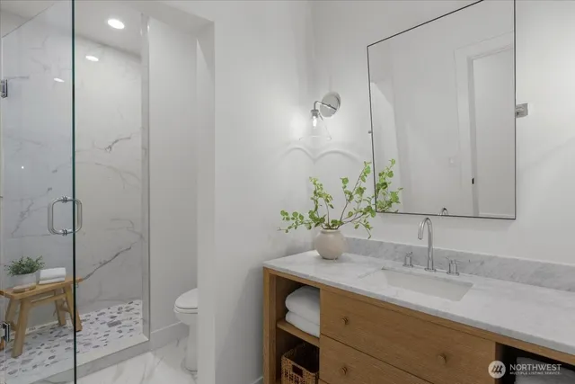 a bathroom with a granite countertop sink a toilet and shower