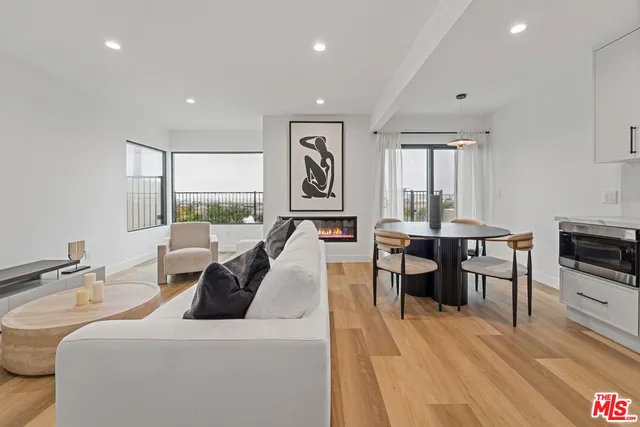 a living room with furniture a large window and wooden floor