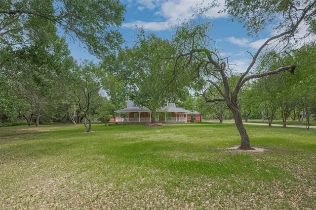 a view of a big yard with a house and large trees