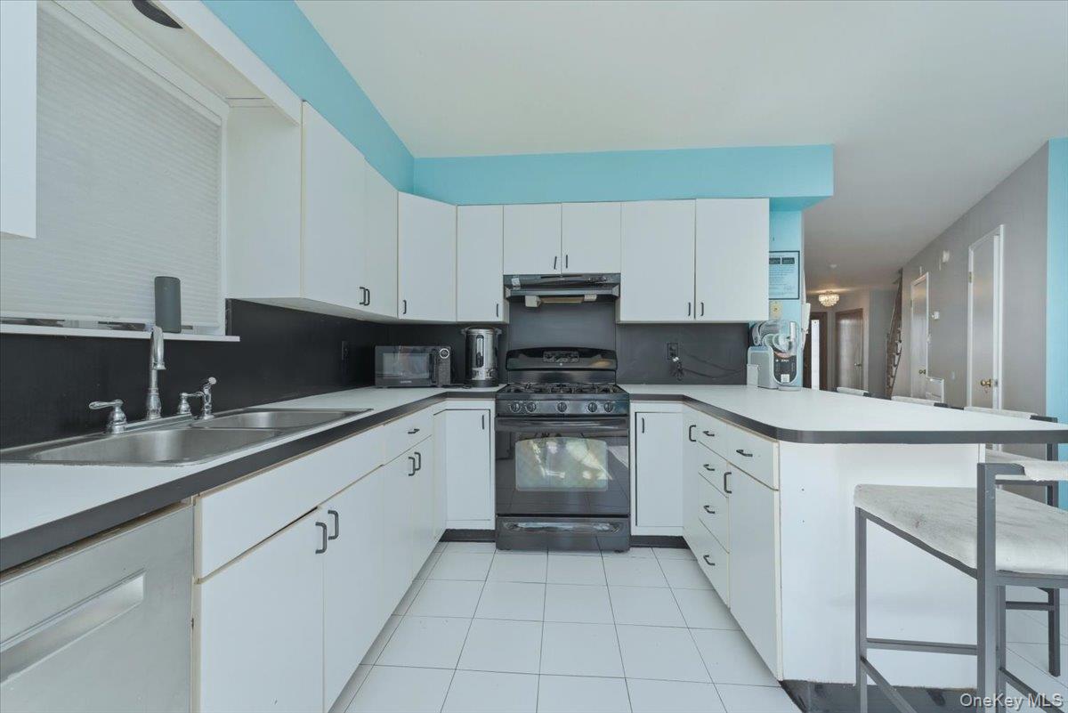 151 Wanser Avenue Inwood, NY 11096 - Photo 8 of 19 a kitchen with granite countertop white cabinets sink and stainless steel appliances
