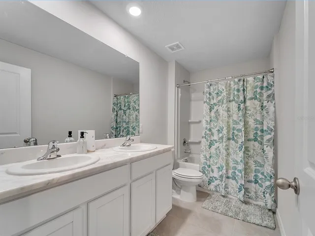 a bathroom with a double vanity sink toilet and a mirror