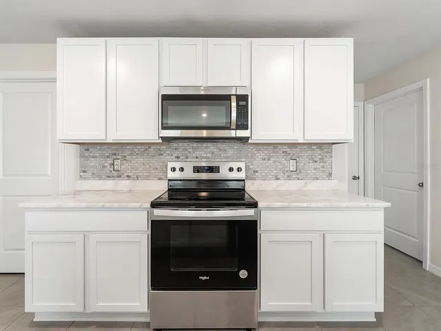 a kitchen with white cabinets and a stove top oven