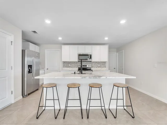 a kitchen with stainless steel appliances granite countertop a table chairs sink and cabinets