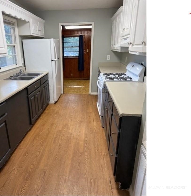 1809 Harris Road Mobile, AL 36618 - Photo 5 of 11 Kitchen featuring white appliances, light countertops, light wood-type flooring, and white cabinets