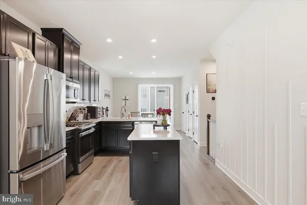 a kitchen with stainless steel appliances granite countertop a refrigerator a stove a sink dishwasher and a refrigerator with wooden floor