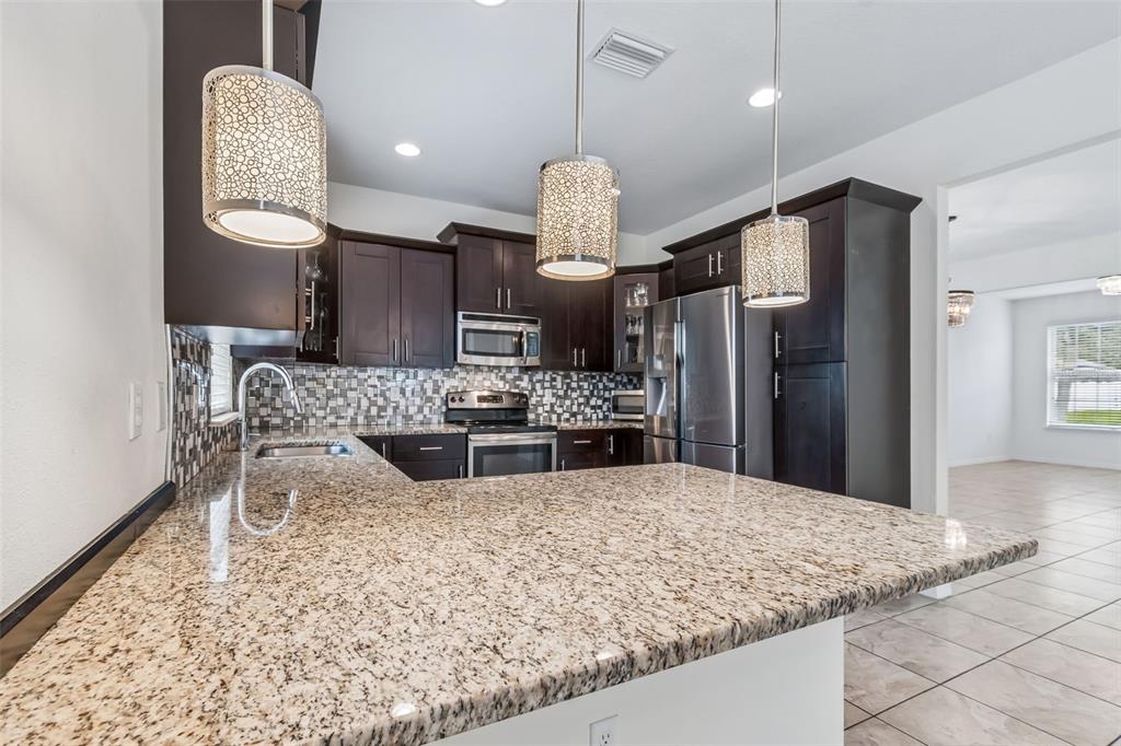 6105 Merrifield Drive Zephyrhills, FL 33541 - Photo 20 of 85 a kitchen with stainless steel appliances kitchen island granite countertop a refrigerator and a sink