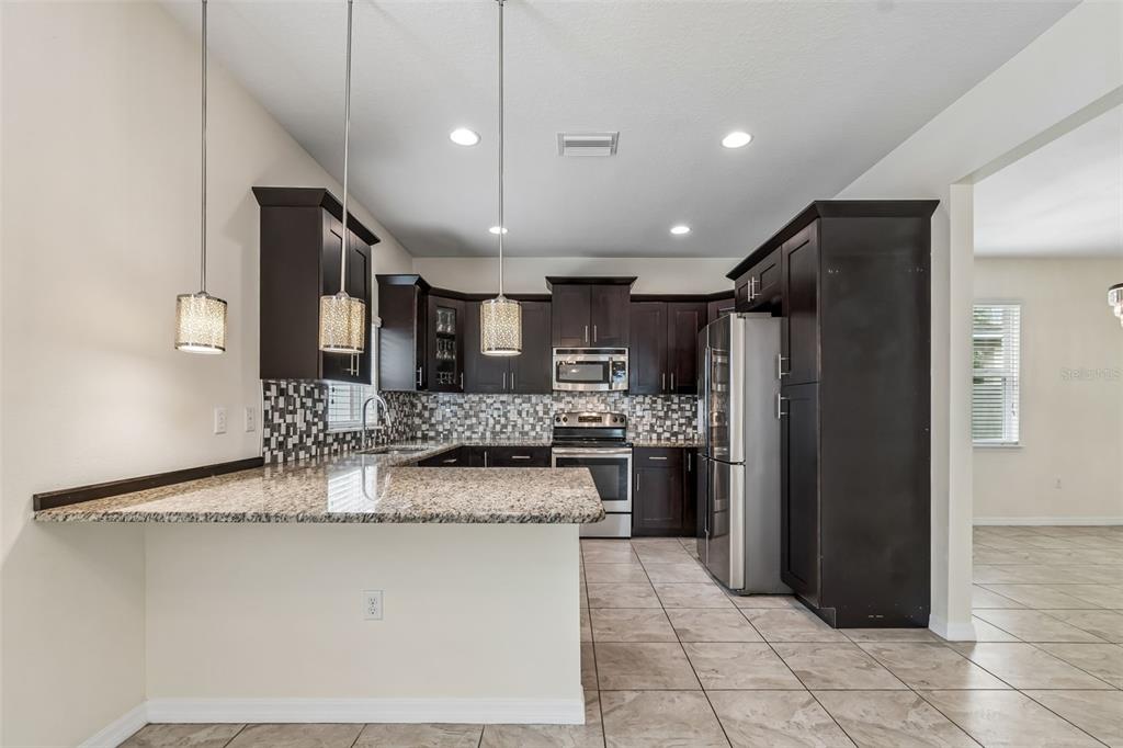 6105 Merrifield Drive Zephyrhills, FL 33541 - Photo 21 of 85 a kitchen with stainless steel appliances granite countertop a refrigerator a stove and a sink