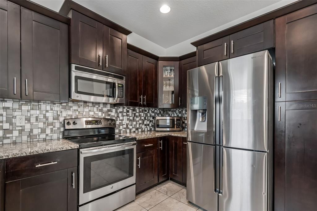 6105 Merrifield Drive Zephyrhills, FL 33541 - Photo 22 of 85 a kitchen with stainless steel appliances granite countertop a refrigerator and a stove top oven