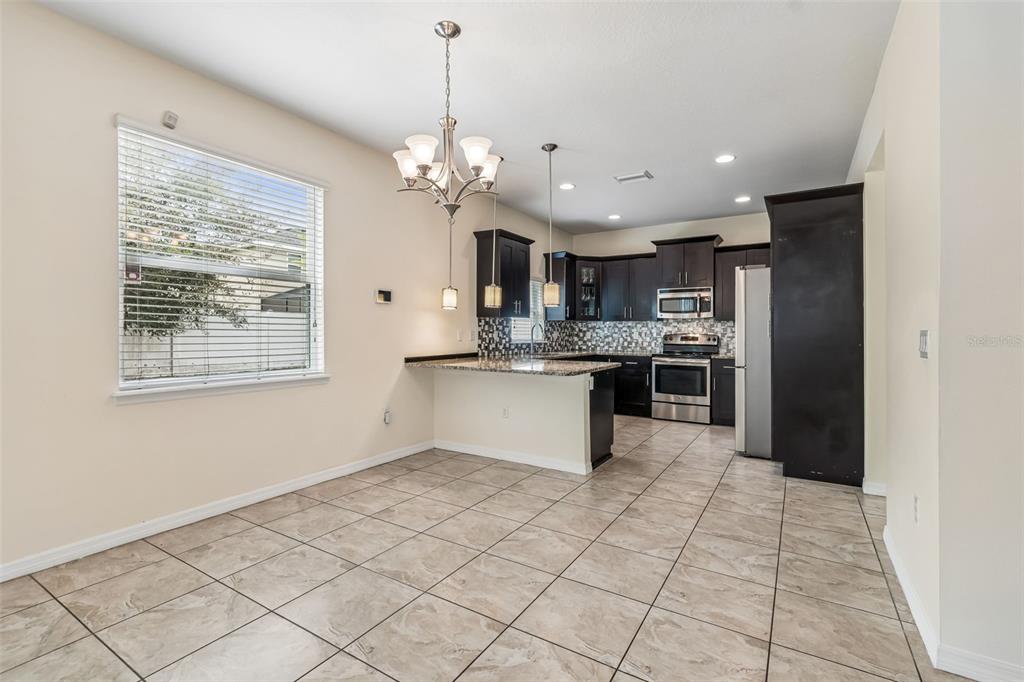 6105 Merrifield Drive Zephyrhills, FL 33541 - Photo 30 of 85 a large white kitchen with kitchen island granite countertop stainless steel appliances cabinets a sink and a counter top space