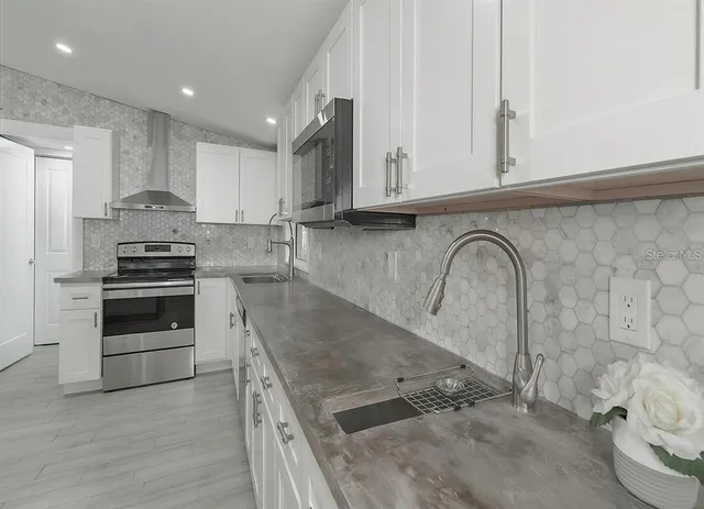 a kitchen with stainless steel appliances granite countertop a stove a sink and a microwave