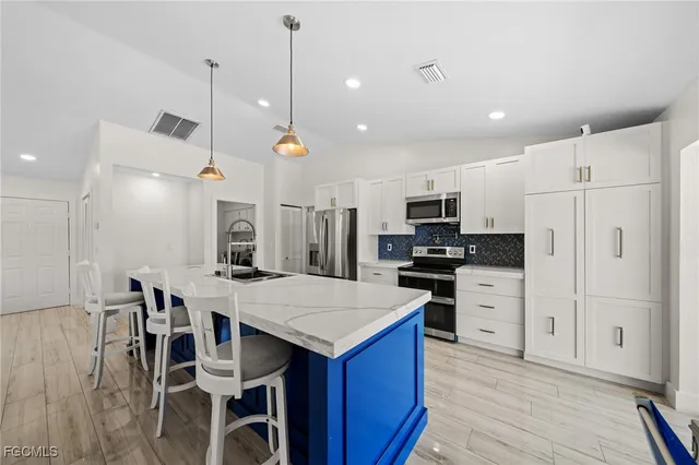 a kitchen with stainless steel appliances kitchen island granite countertop a refrigerator a stove a microwave oven a sink with island and chairs with wooden floor