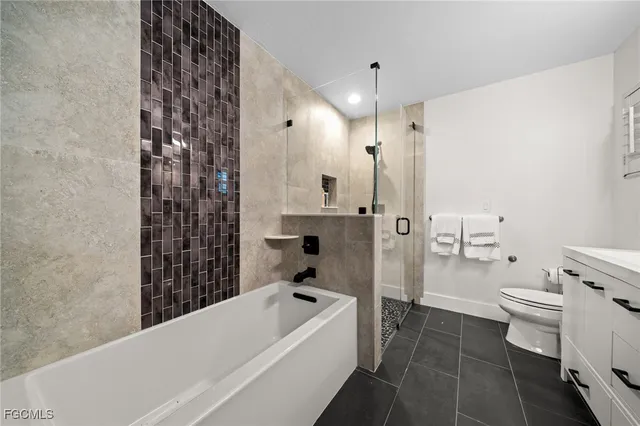 a bathroom with a granite countertop bathtub sink vanity mirror and toilet