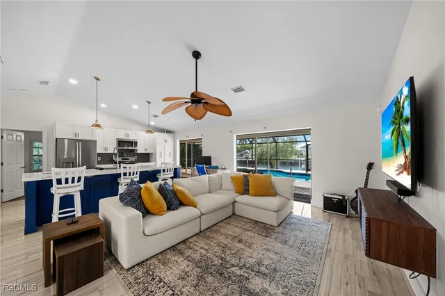 a living room with stainless steel appliances furniture and a flat screen tv