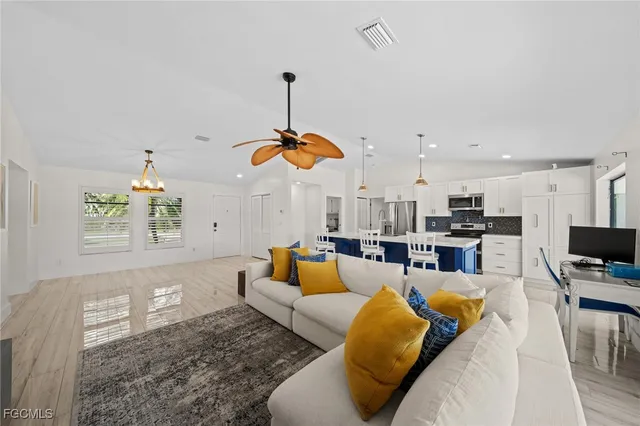 a living room with furniture kitchen view and a chandelier
