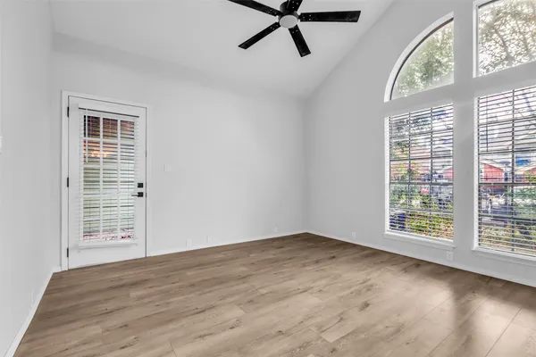 a view of an empty room with a window and wooden floor