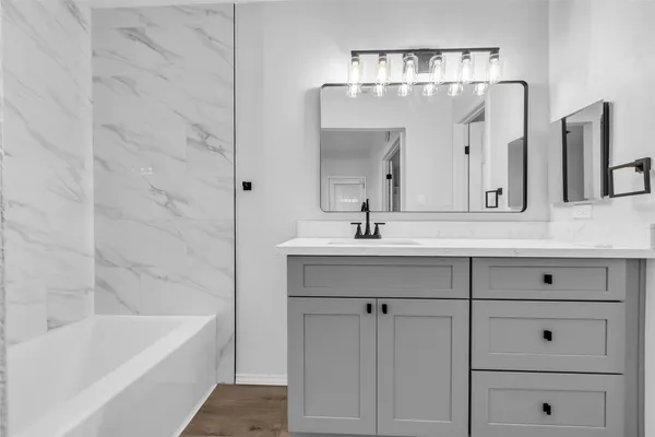 a bathroom with a bathtub a sink and mirror