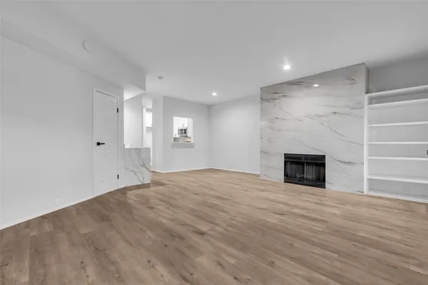 a view of empty room with wooden floor and fireplace