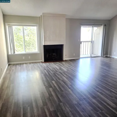 an empty room with wooden floor fireplace and windows