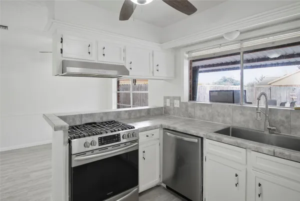 a kitchen with granite countertop a sink stainless steel appliances and cabinets