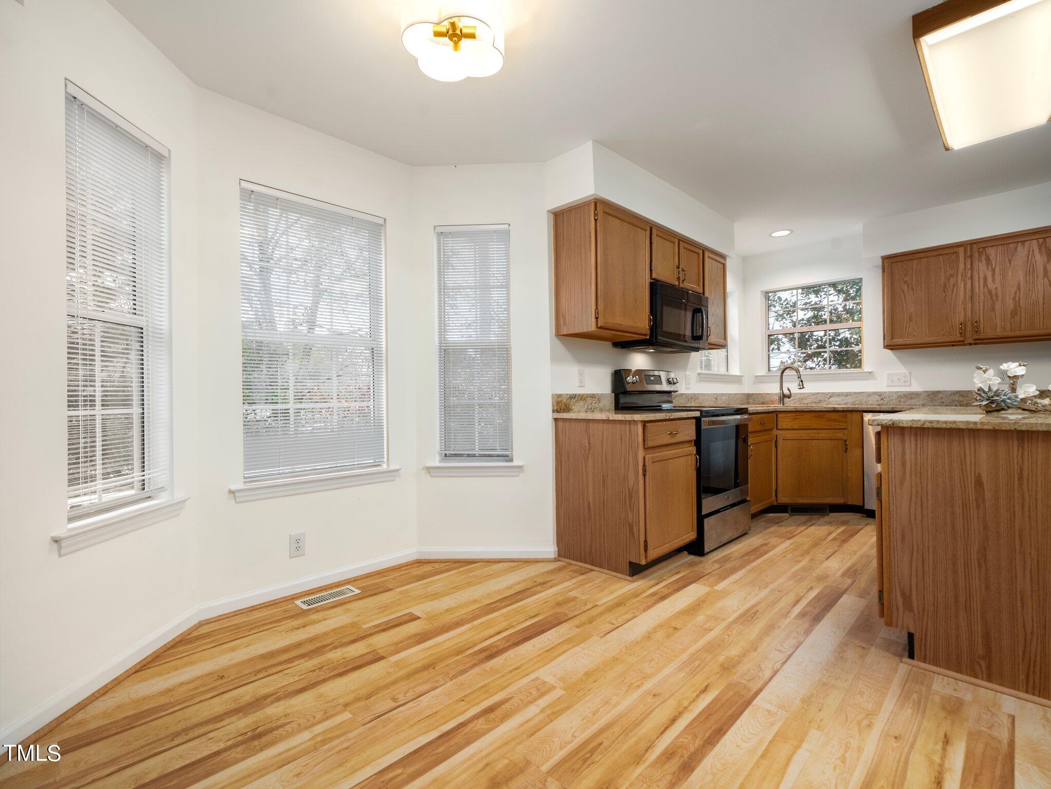 112 Riva Trace Drive Cary, NC 27513 - Photo 7 of 29 a kitchen with stainless steel appliances granite countertop a stove top oven a sink dishwasher and a microwave with wooden floor