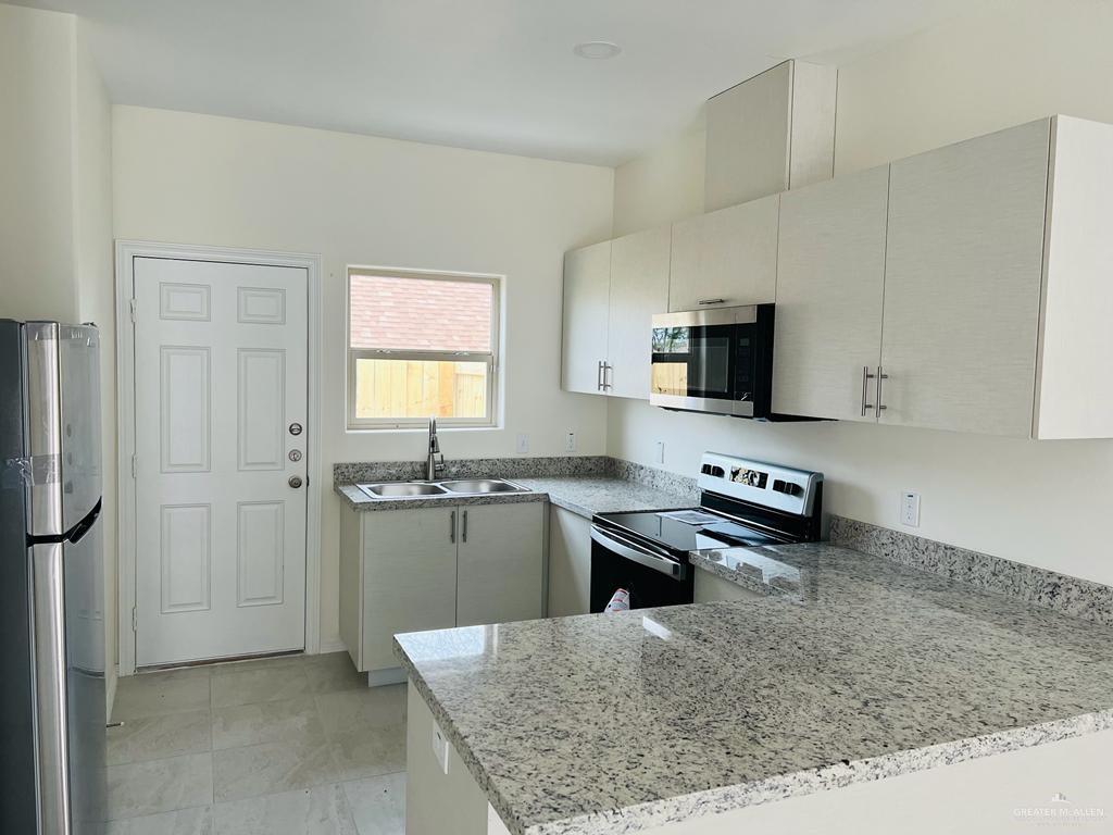 1201 West Garfield Avenue, Unit 3 Alton, TX 78573 - Photo 3 of 15 a kitchen with a refrigerator and a stove top oven