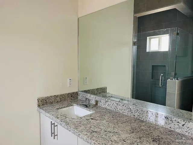 a bathroom with a granite countertop sink and a mirror