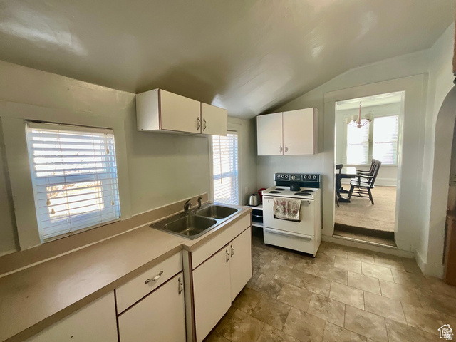 495 North Main Street Beaver, UT 84713 - Photo 7 of 18 Kitchen with white electric stove, light countertops, vaulted ceiling, white cabinetry, and plenty of natural light