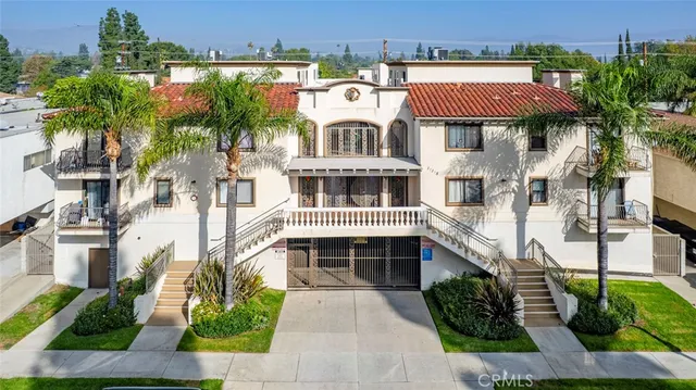 a front view of a multi story residential apartment building with a yard and potted plants