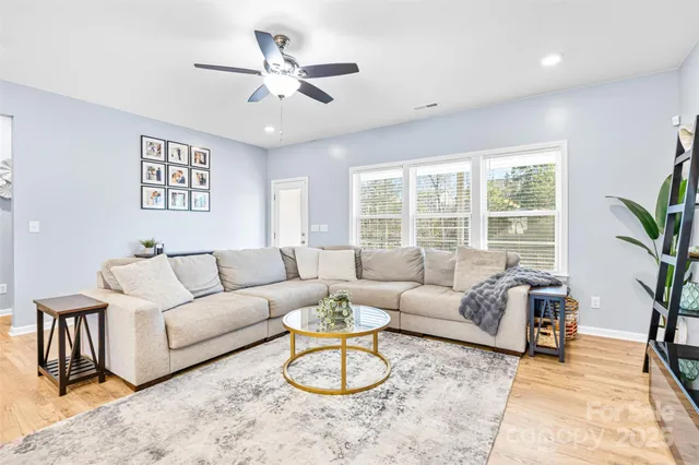 a living room with furniture ceiling fan and a large window