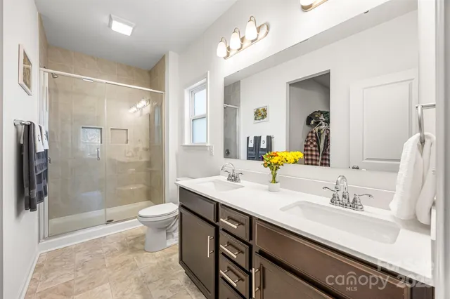 a bathroom with a double vanity sink toilet and shower