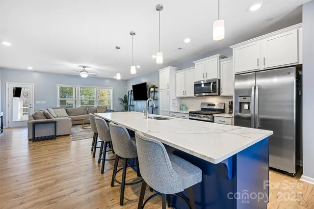 a kitchen with kitchen island a refrigerator a stove a dining table and chairs with wooden floor