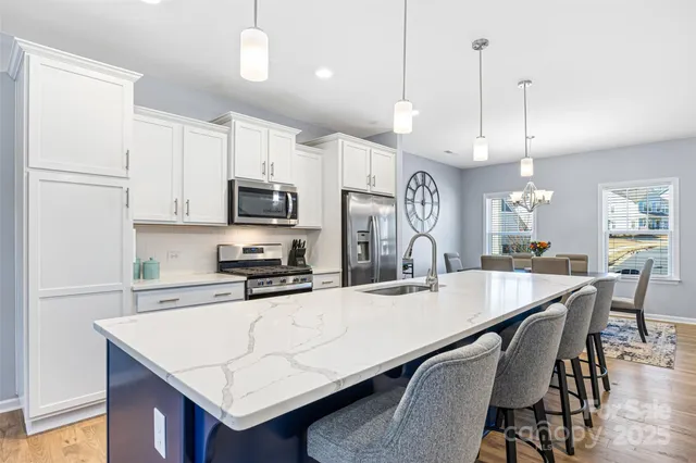 a kitchen with granite countertop a table chairs stainless steel appliances and cabinets