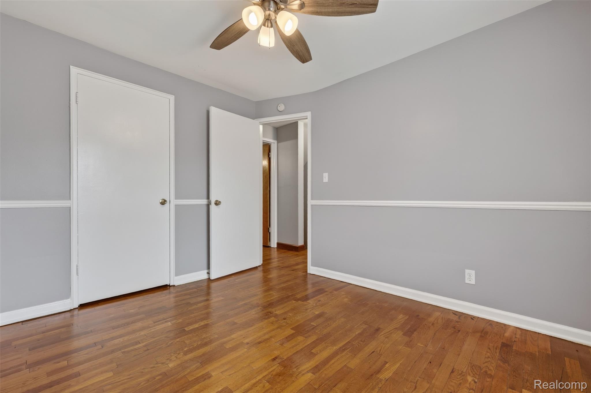 316 Sheffield Avenue Flint, MI 48503 - Photo 17 of 37 Hardwood flooring, painted walls with chair rail molding, ceiling fan with integrated lighting, and white paneled doors